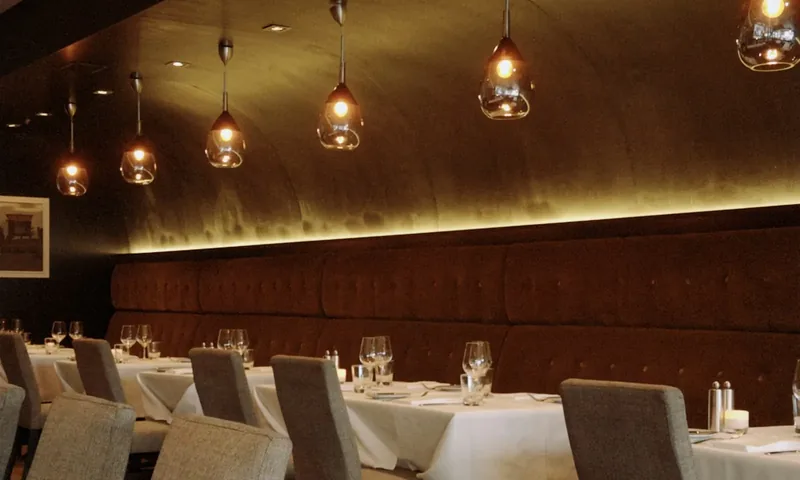 Een restaurant in de avond: gedekte tafels met wit linnen onder warme hanglampen